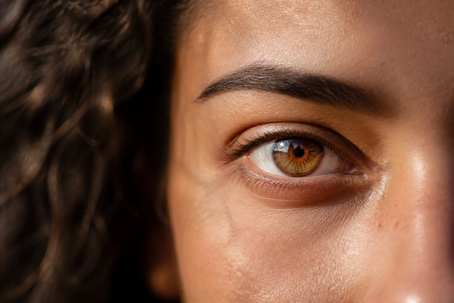 Couleurs yeux : gros plan réaliste d’un visage avec iris noisette-vert, lumière naturelle et fond chaleureux.